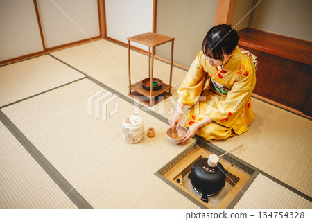 一位年輕貌美的和服女子正在日式房間裡進行茶道表演。 134754328