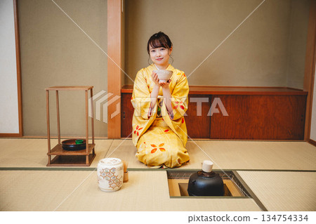 一位年輕貌美的和服女子正在日式房間裡進行茶道表演。 一位年輕貌美的和服女子正在日式房間裡進行茶道表演。 134754334