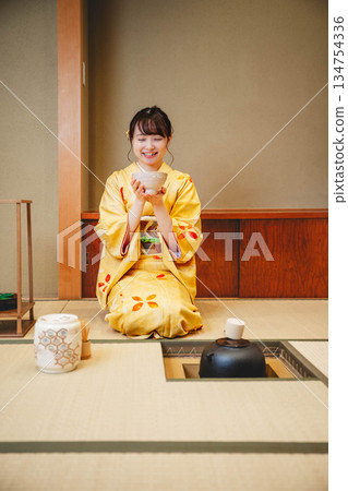 一位年輕貌美的和服女子正在日式房間裡進行茶道表演。 一位年輕貌美的和服女子正在日式房間裡進行茶道表演。 134754336