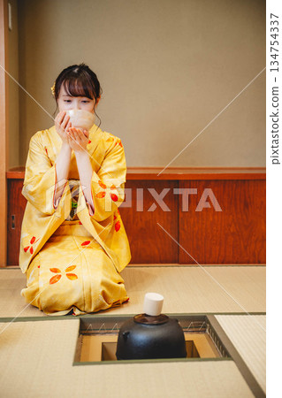 A young and beautiful kimono woman performing a tea ceremony in a Japanese-style room 134754337