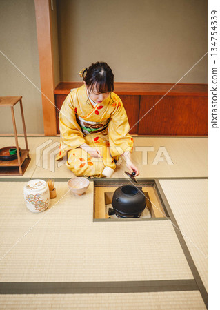 一位年輕貌美的和服女子正在日式房間裡進行茶道表演。 一位年輕貌美的和服女子正在日式房間裡進行茶道表演。 134754339