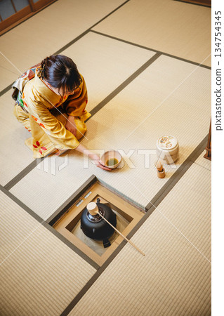 一位年輕貌美的和服女子正在日式房間裡進行茶道表演。 134754345