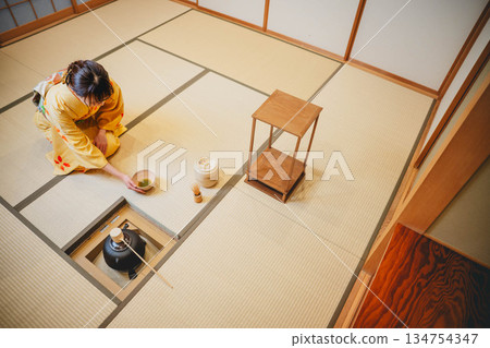 一位年輕貌美的和服女子正在日式房間裡進行茶道表演。 一位年輕貌美的和服女子正在日式房間裡進行茶道表演。 134754347