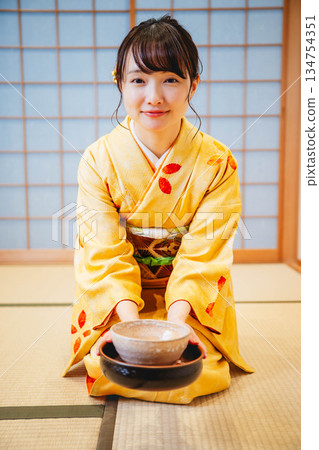 一位年輕貌美的和服女子正在日式房間裡進行茶道表演。 134754351