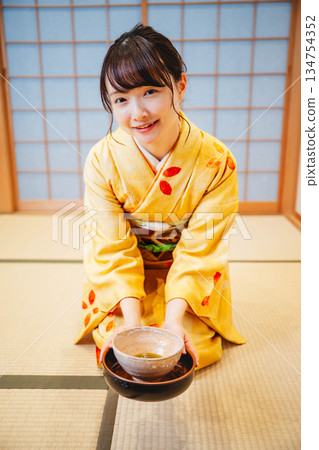 一位年輕貌美的和服女子正在日式房間裡進行茶道表演。 134754352