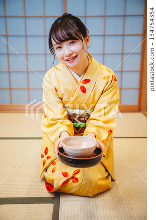 一位年輕貌美的和服女子正在日式房間裡進行茶道表演。 134754354