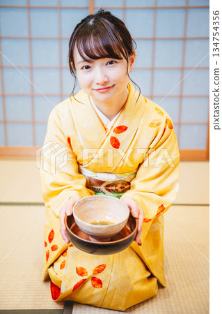 一位年輕貌美的和服女子正在日式房間裡進行茶道表演。 一位年輕貌美的和服女子正在日式房間裡進行茶道表演。 134754356