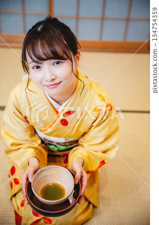 一位年輕貌美的和服女子正在日式房間裡進行茶道表演。 一位年輕貌美的和服女子正在日式房間裡進行茶道表演。 134754359