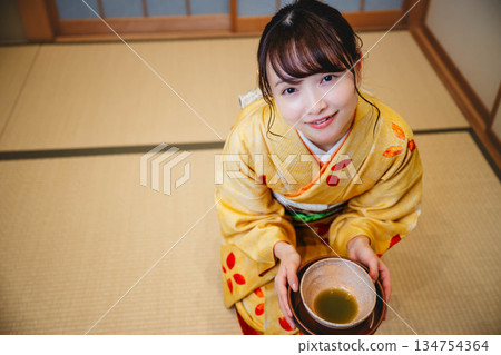 一位年輕貌美的和服女子正在日式房間裡進行茶道表演。 134754364