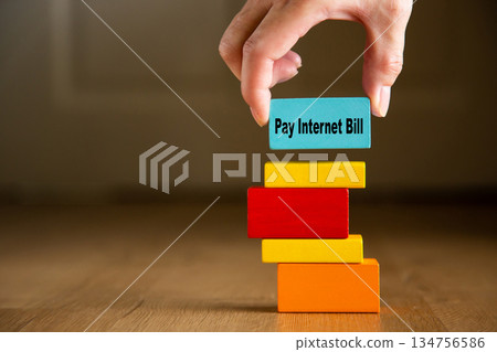 Hand placing pay internet bill block on spending stack 134756586