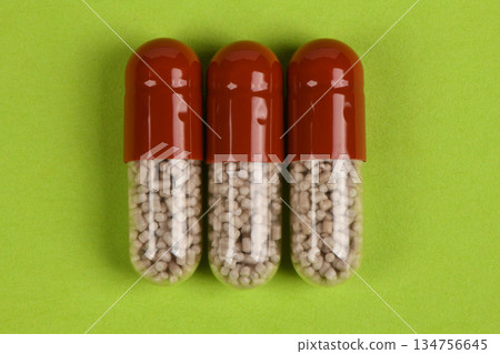 Three Pharmaceutical Capsules on Green Background Healthcare Concept Three Pharmaceutical Capsules on Green Background Healthcare Concept 134756645