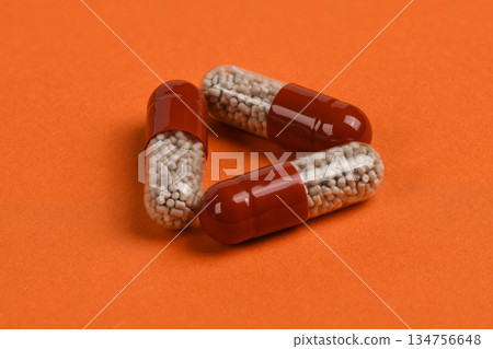 Three Medicine Capsules Arranged in Triangle on Orange Background Three Medicine Capsules Arranged in Triangle on Orange Background 134756648