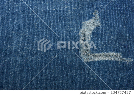 Ripped blue hipster jeans material. Destroyed denim Cloth texture. Close up. Ripped blue hipster jeans material. Destroyed denim Cloth texture. Close up. 134757437