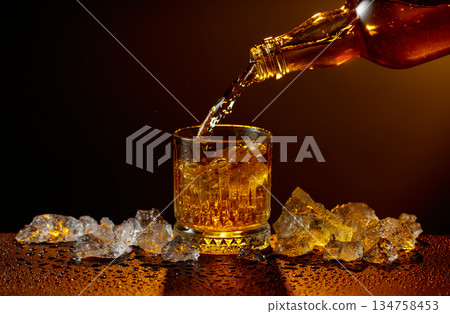 Whiskey pours from bottle to glass. Whiskey pours from bottle to glass. 134758453