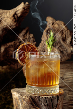 An old-fashioned cocktail over ice on an old wooden stump. An old-fashioned cocktail over ice on an old wooden stump. 134758480