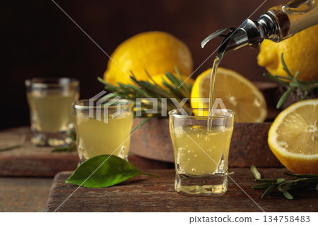 Italian liqueur Limoncello with fresh lemons and rosemary branches. Italian liqueur Limoncello with fresh lemons and rosemary branches. 134758483