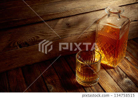 Elegant whiskey glass and decanter on a old wooden table. 134758515