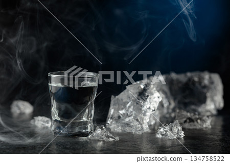 Crystal clear vodka in a glass on a black stone table. Crystal clear vodka in a glass on a black stone table. 134758522