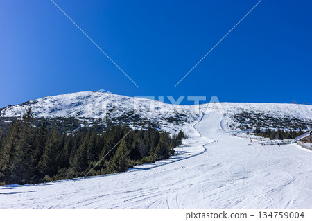 Empty groomed ski slope under a clear blue sky in the mountains. Empty groomed ski slope under a clear blue sky in the mountains. 134759004