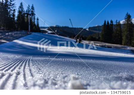 Close-up of freshly groomed corduroy snow on a ski slope. Close-up of freshly groomed corduroy snow on a ski slope. 134759015