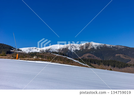 Empty groomed ski slope under a clear blue sky in the mountains. Empty groomed ski slope under a clear blue sky in the mountains. 134759019