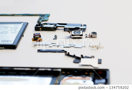 Internal components of a disassembled smartphone, including the camera module, battery, and motherboard parts, laid out on a white surface. Concept of electronics repair and high-tech hardware 134759202