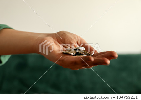 Close-up of a dirty hand holding a small pile of silver coins. Concept of poverty, begging, or hard-earned money Close-up of a dirty hand holding a small pile of silver coins. Concept of poverty, begging, or hard-earned money 134759211