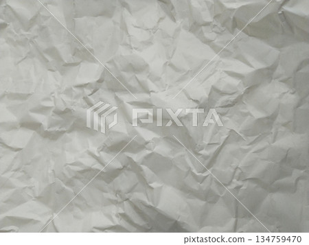 Abstract texture of crumpled paper. The paper exhibits numerous folds, wrinkles, and shadows 134759470