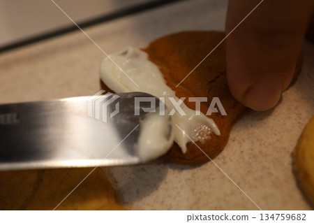 Close-up of hands decorating cookies with icing Close-up of hands decorating cookies with icing 134759682