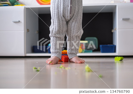 Toddler with Bare Legs Standing on Floor Surrounded by Broccoli 134760790