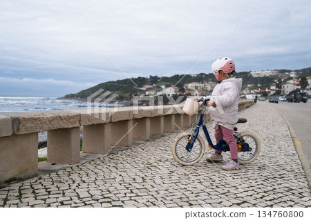 Little girl riding a two wheeled bicycle wearing a helmet Little girl riding a two wheeled bicycle wearing a helmet 134760800