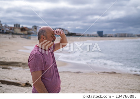 An elderly man with a mustache walking on the beach, enjoying his vacation. An elderly man with a mustache walking on the beach, enjoying his vacation. 134760895