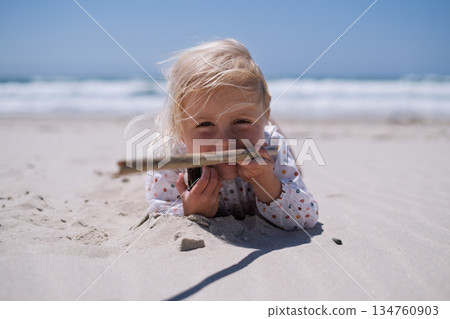 Little Girl Playing Alone in the Sand on the Beach 134760903