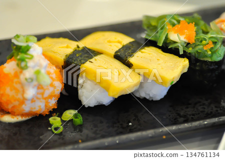 sushi or egg sushi , rice topped with egg and shrimp sushi or steam egg roll and seaweed roll 134761134