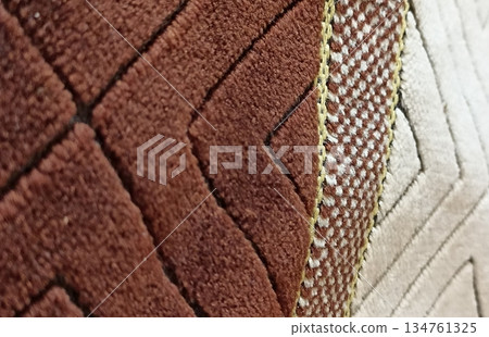 Close-up of a geometric patterned rug in brown, beige, and cream colors. The abstract shapes create a textured design, ideal for backgrounds and interior design projects. Close-up of a geometric patterned rug in brown, beige, and cream colors. The abstract shapes create a textured design, ideal for backgrounds and interior design projects. 134761325