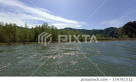 Discover a peaceful river flowing through a lush green forest, framed by a stunning rocky cliff. Ideal for tourism and inspiration, this scene captures the beauty of nature. 134761512