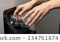 Ultra-detailed close-up of human hands inserting a transparent plastic bottle into an automated recycling machine 134761874