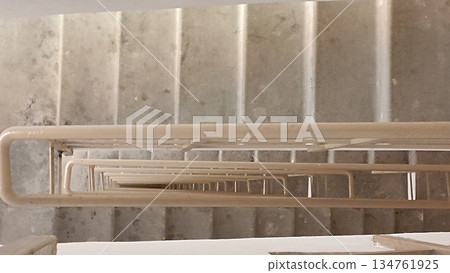 A captivating view down a flight of stairs, showcasing repeating patterns of steps and handrails. This image evokes depth and perspective, ideal for concepts like descent and architectural design. 134761925