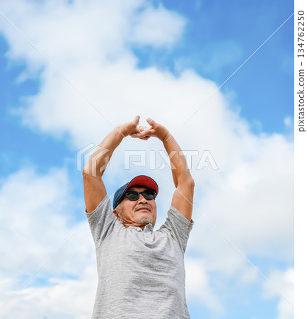 A man stretching outdoors, looking up at the sky 134762250