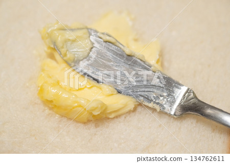 圖片展示了在麵包上塗抹人造奶油的過程 134762611