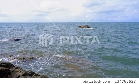 Isolated Rock Formation in the Middle of Calm Sea Water 134762628