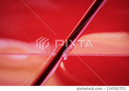 Closeup of red car with paint damage, long scratch 134762731