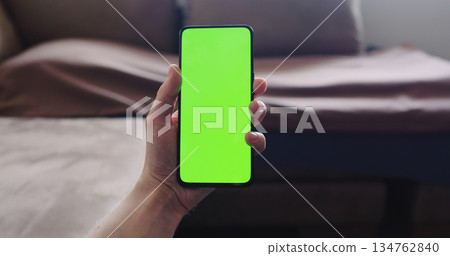 Closeup young man sit on a couch and show smartphone with green screen Closeup young man sit on a couch and show smartphone with green screen 134762840