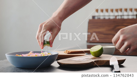 Man squeeze lime into greek salad in blue bowl Man squeeze lime into greek salad in blue bowl 134762843