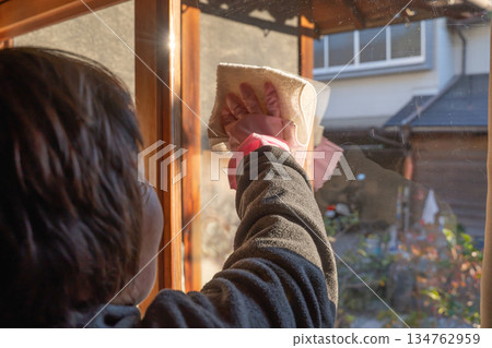 一位老婦人戴著橡膠手套擦拭窗戶 134762959
