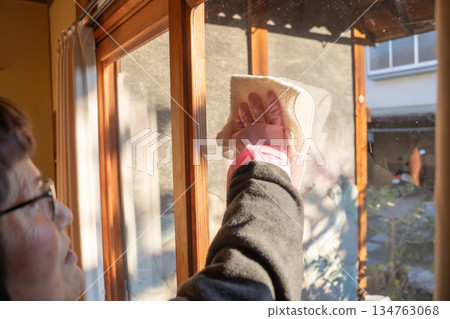 Elderly woman cleaning windows 134763068