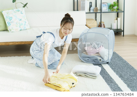 年輕女子在客廳裡疊衣服 134763484