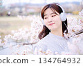 Young woman enjoying music under the cherry blossom tree 134764932