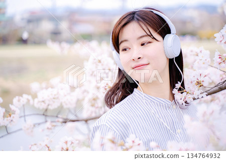 Young woman enjoying music under the cherry blossom tree Young woman enjoying music under the cherry blossom tree 134764932