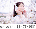 Young woman enjoying music under the cherry blossom tree 134764935